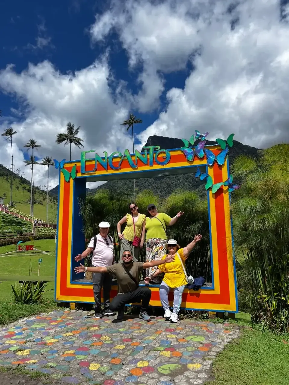 Un grupo de viajeros posando en un marco de colores entre las palmas de cera del Valle de Cocora.